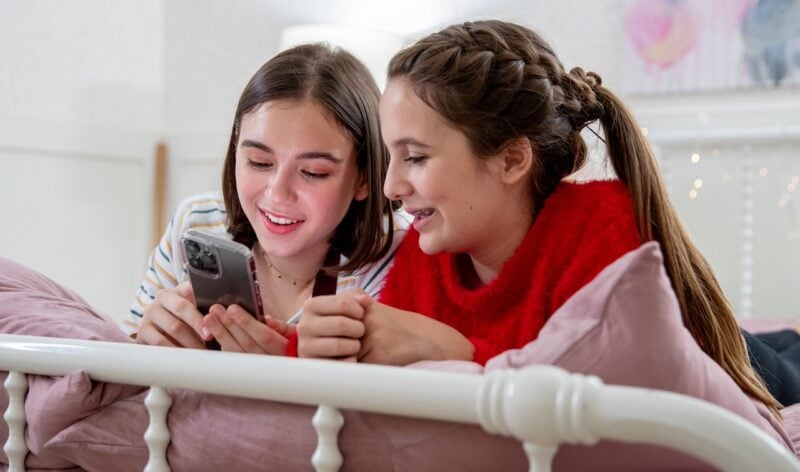 Two smiling girls looking at a phone