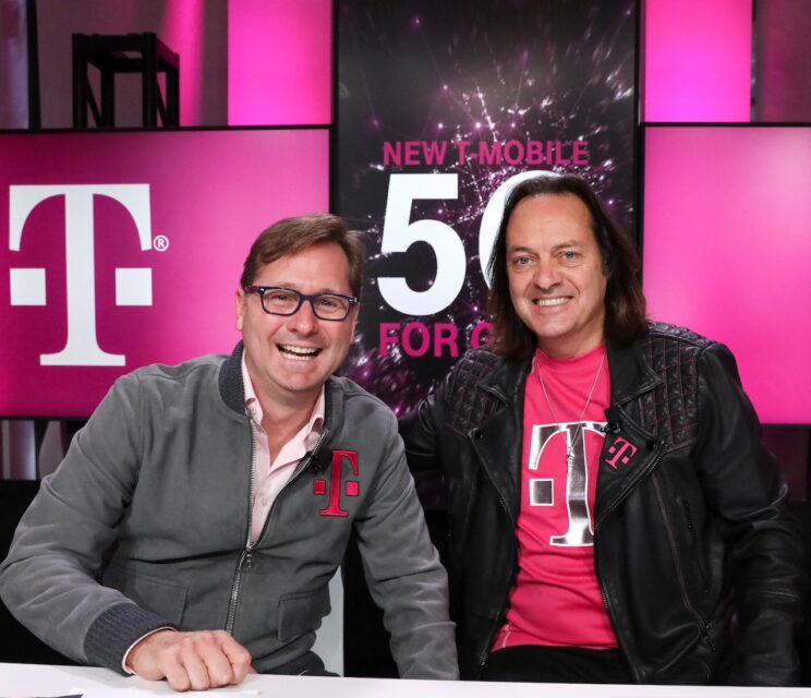 John Legere and Mike Sievert sitting beside each other smiling 