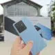 Hand holding blue Realme GT 7 with phone poster in background