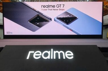 Glowing Realme sign with GT 7 phone series launch banner behind it
