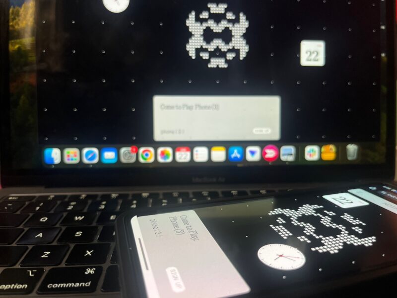 Phone resting on laptop keyboard with both devices showing Nothing Phone 3 glyph matrix design on screen