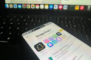 Phone resting on laptop keyboard showing Snapchat Plus perks menu