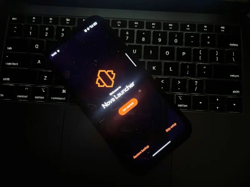 Darkened shot of phone resting on laptop keyboard while displaying Nova Launcher welcome screen