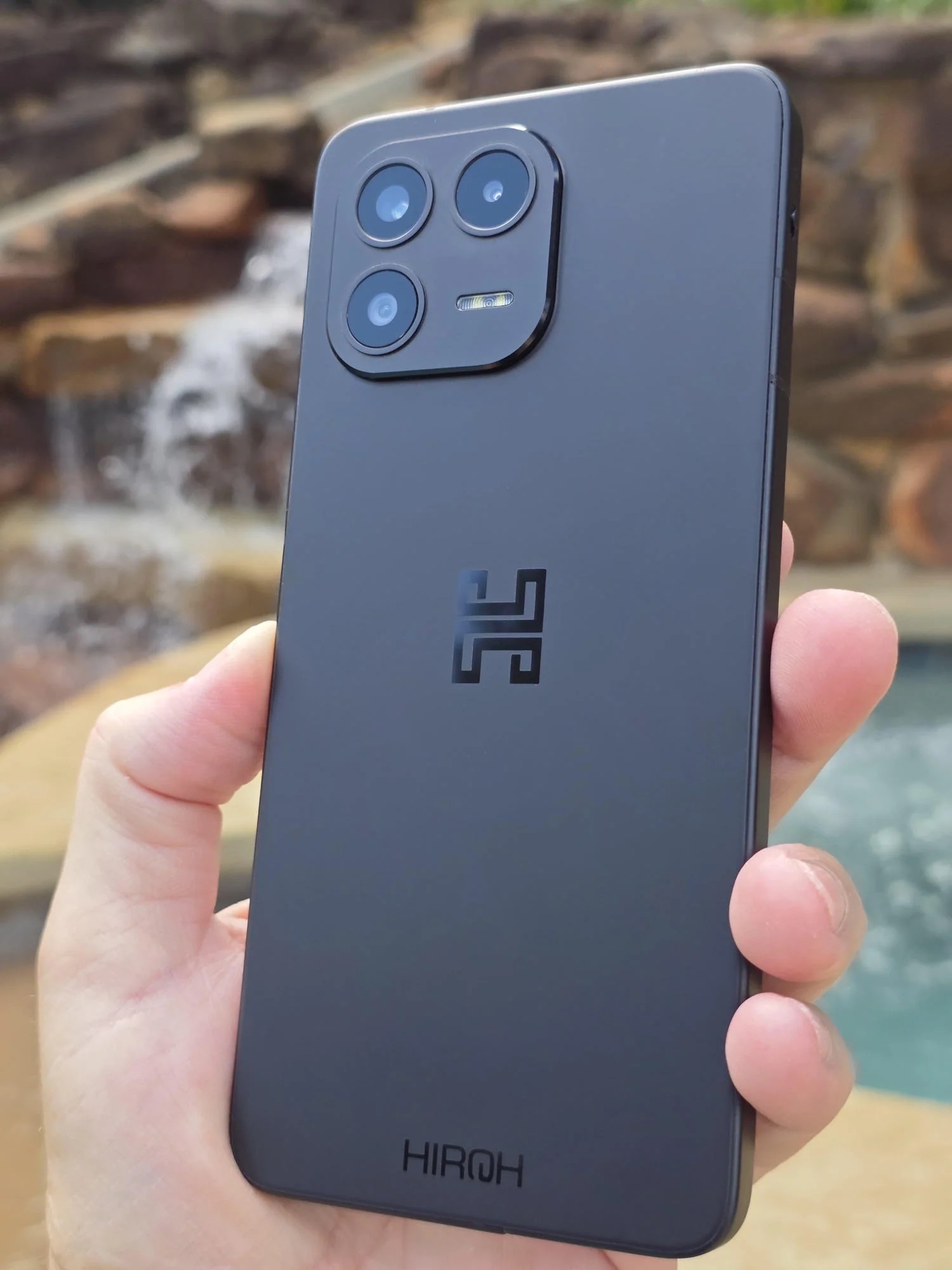 Hand holding black Hiroh Phone with back facing camera