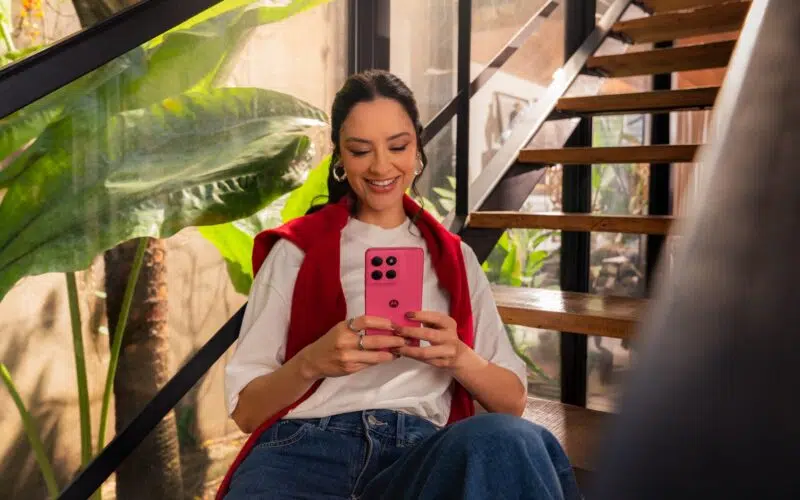 Smiling woman using pink Moto G57