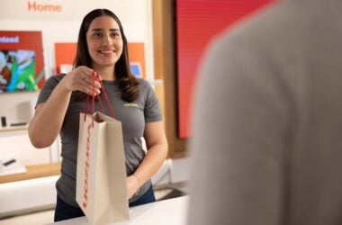 Smiling Verizon staff holding paper shopping bag