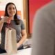 Smiling Verizon staff holding paper shopping bag