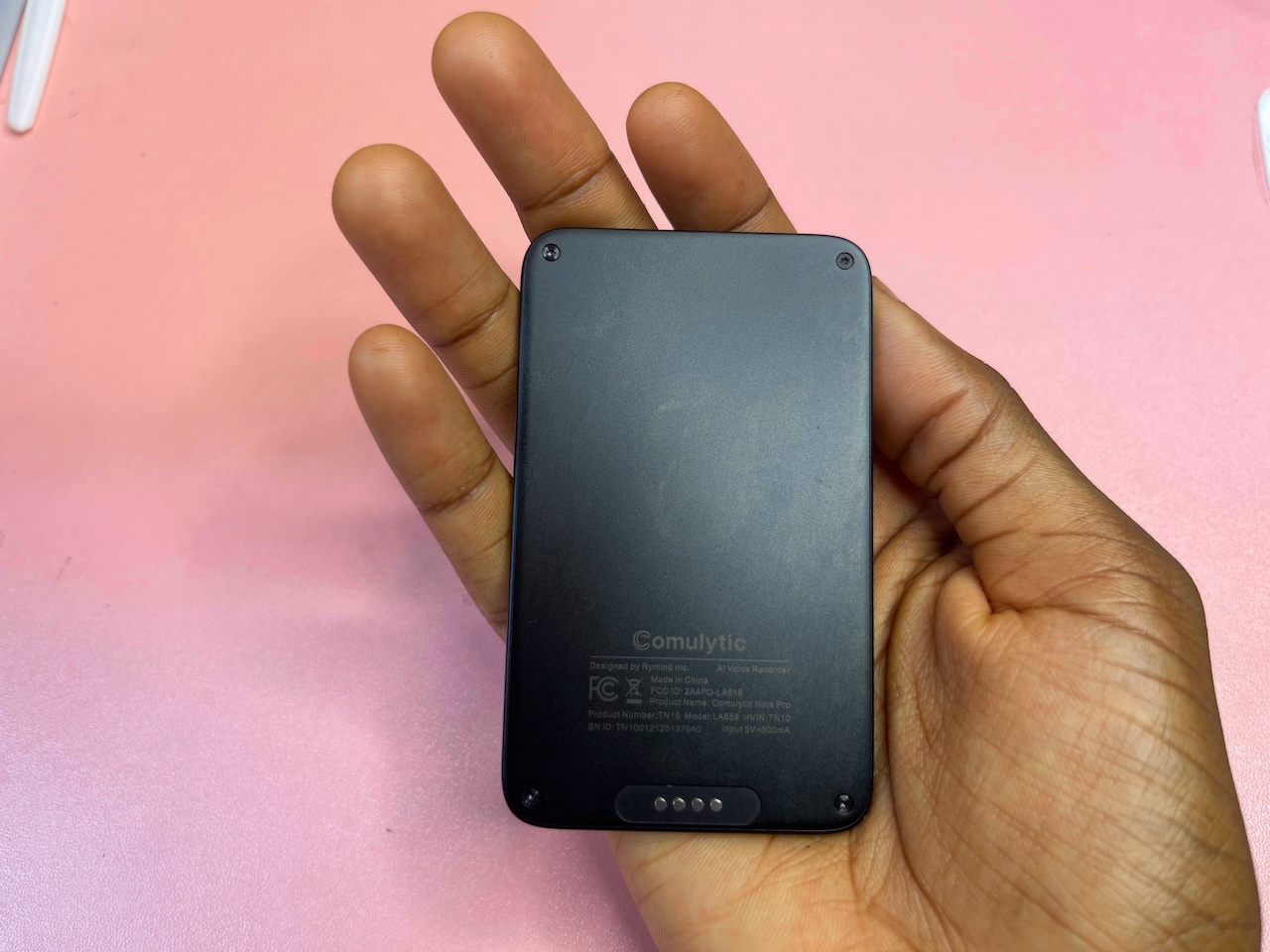 Hand holding Comulytic Note Pro with back side facing up