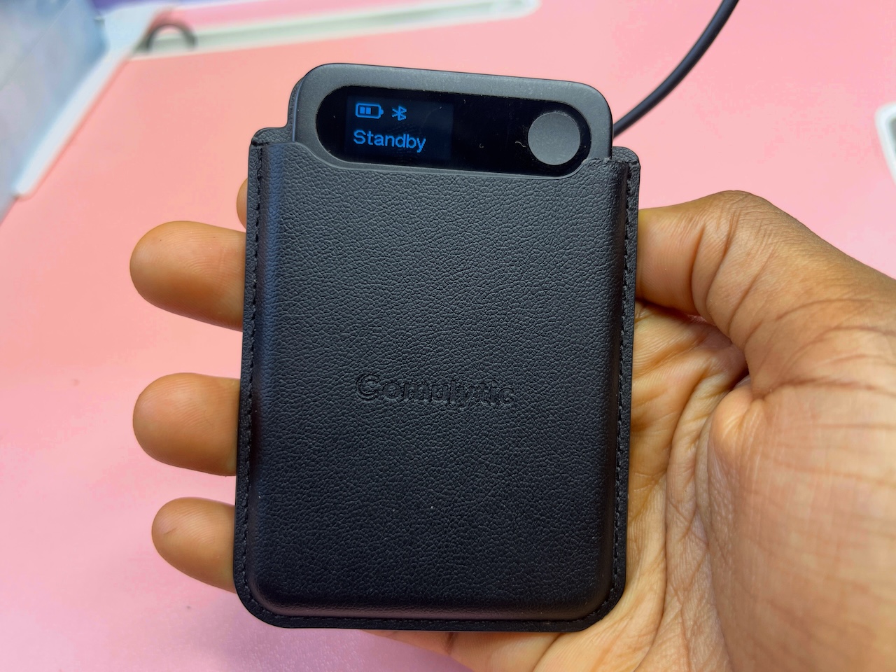 Hand holding Comulytic Note Pro with display on