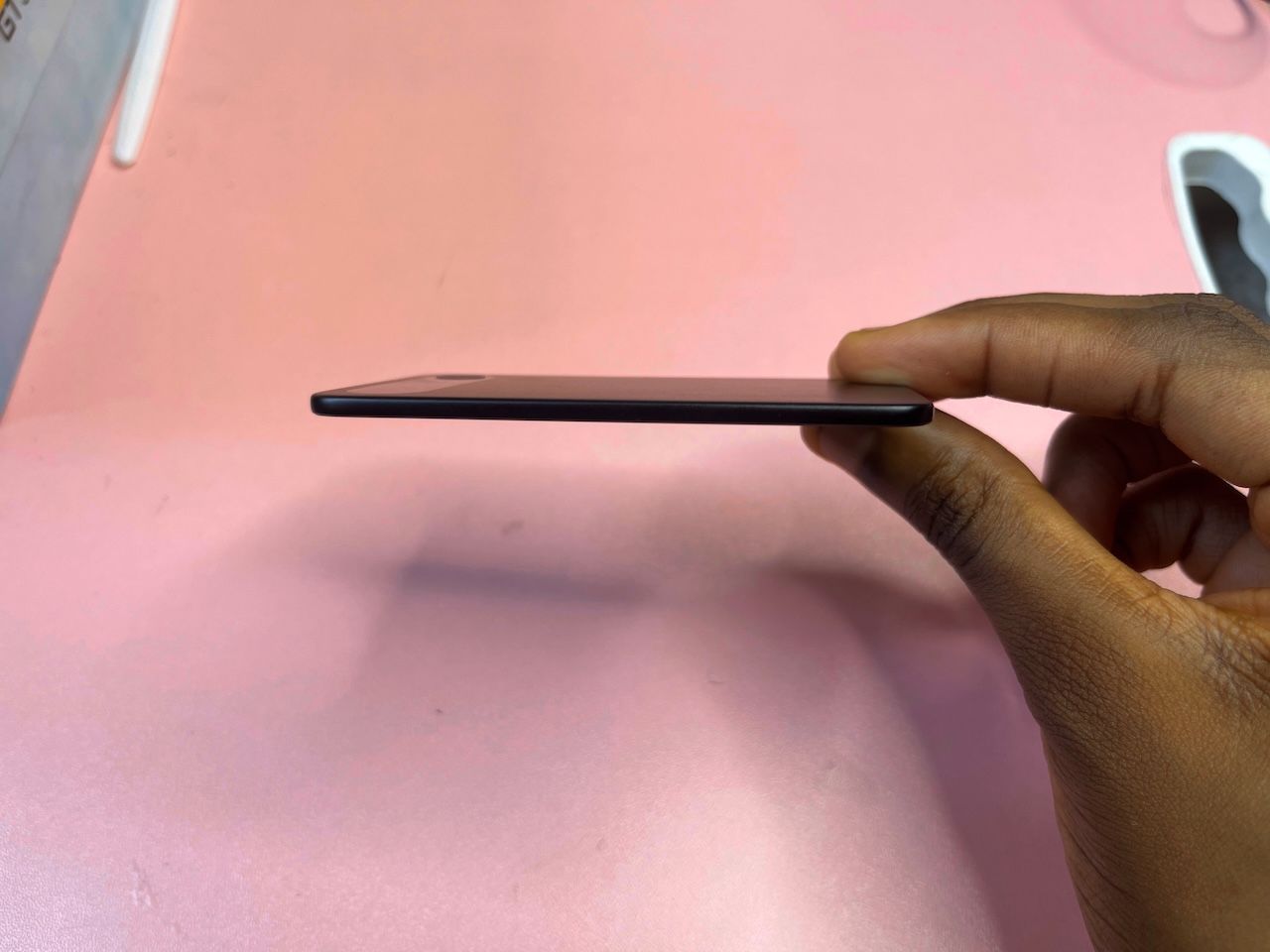 Hand holding Comulytic Note Pro at the edges to show thin side view