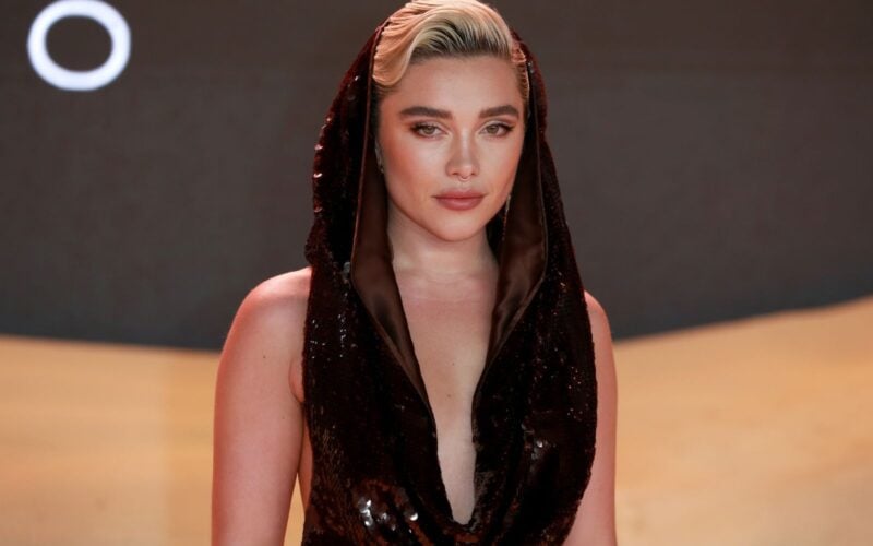 Florence Pugh wearing a black sequined hooded dress at a red carpet event.