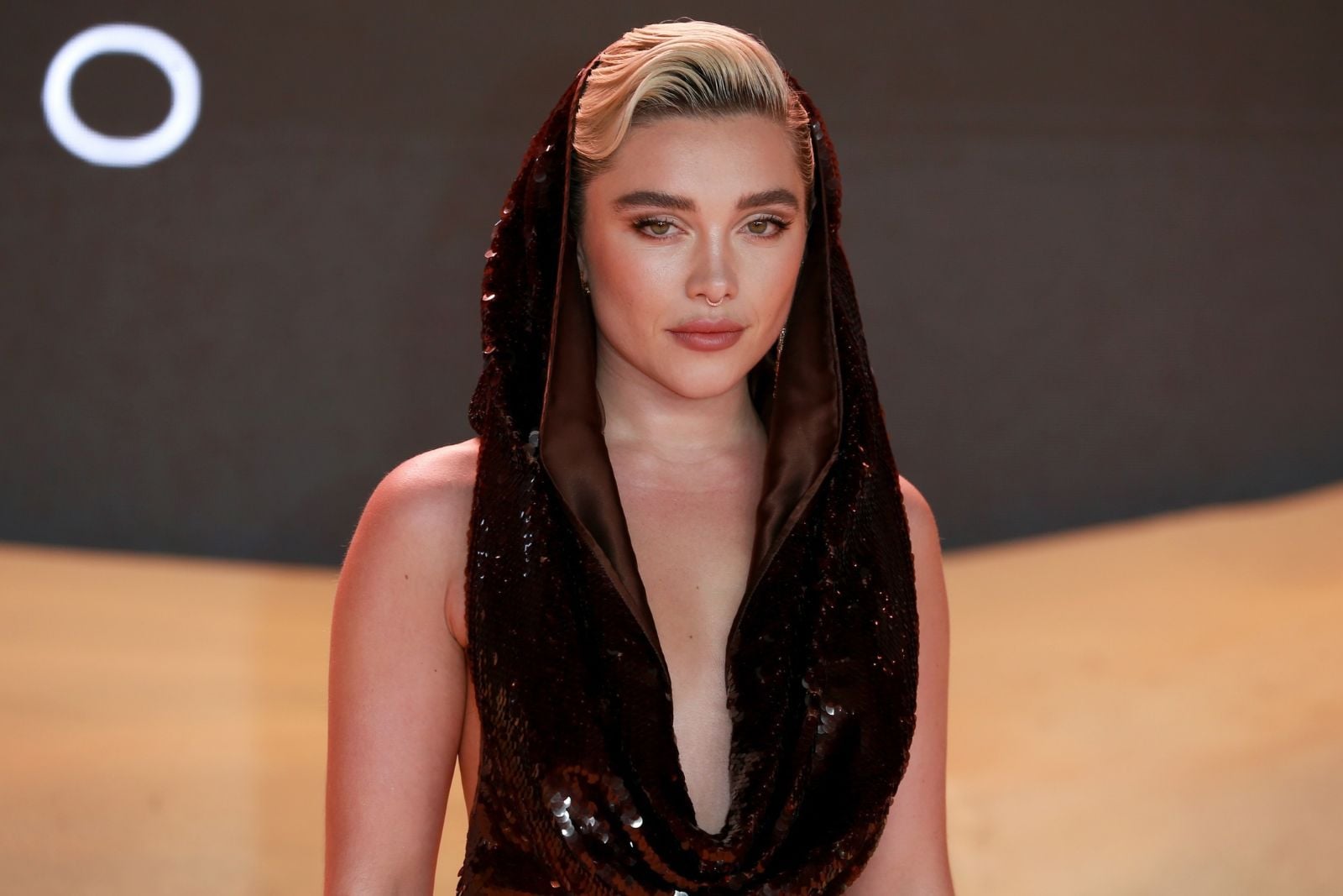 Florence Pugh wearing a black sequined hooded dress at a red carpet event.