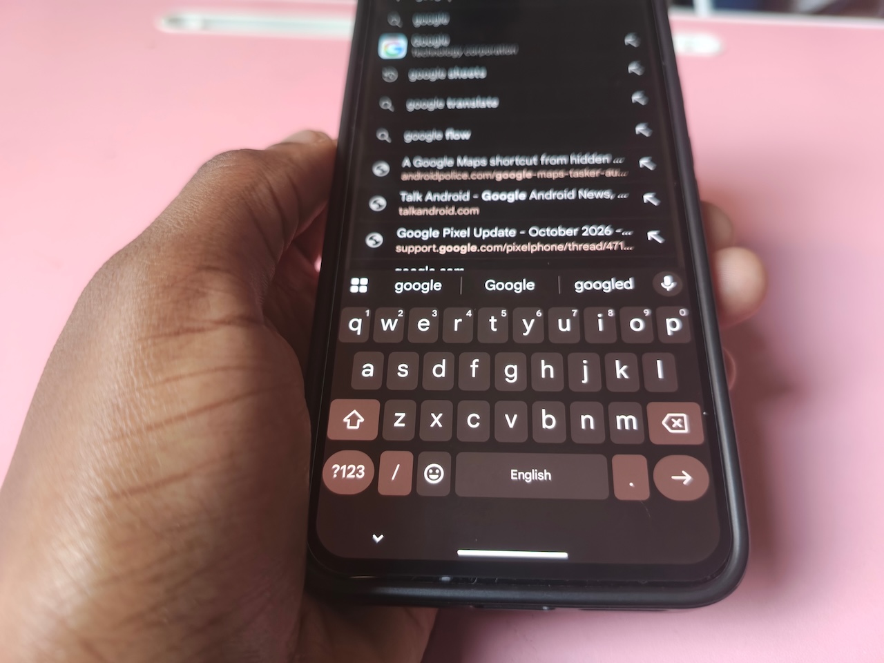 Hand holding phone with Gboard open under Google Search bar