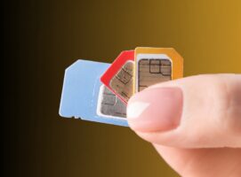 Hand holding three SIM cards in blue, red, and orange