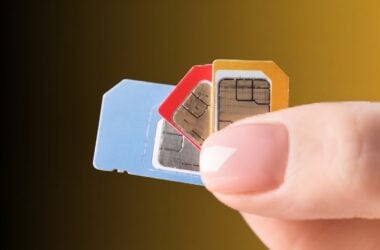 Hand holding three SIM cards in blue, red, and orange