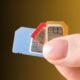 Hand holding three SIM cards in blue, red, and orange