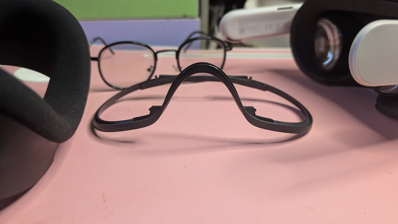 Meta Quest 3s eyeglass spacer accessory resting on surface alongside a pair of glasses