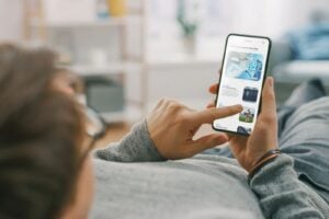 Person scrolling through news articles on a smartphone while relaxing on a couch.
