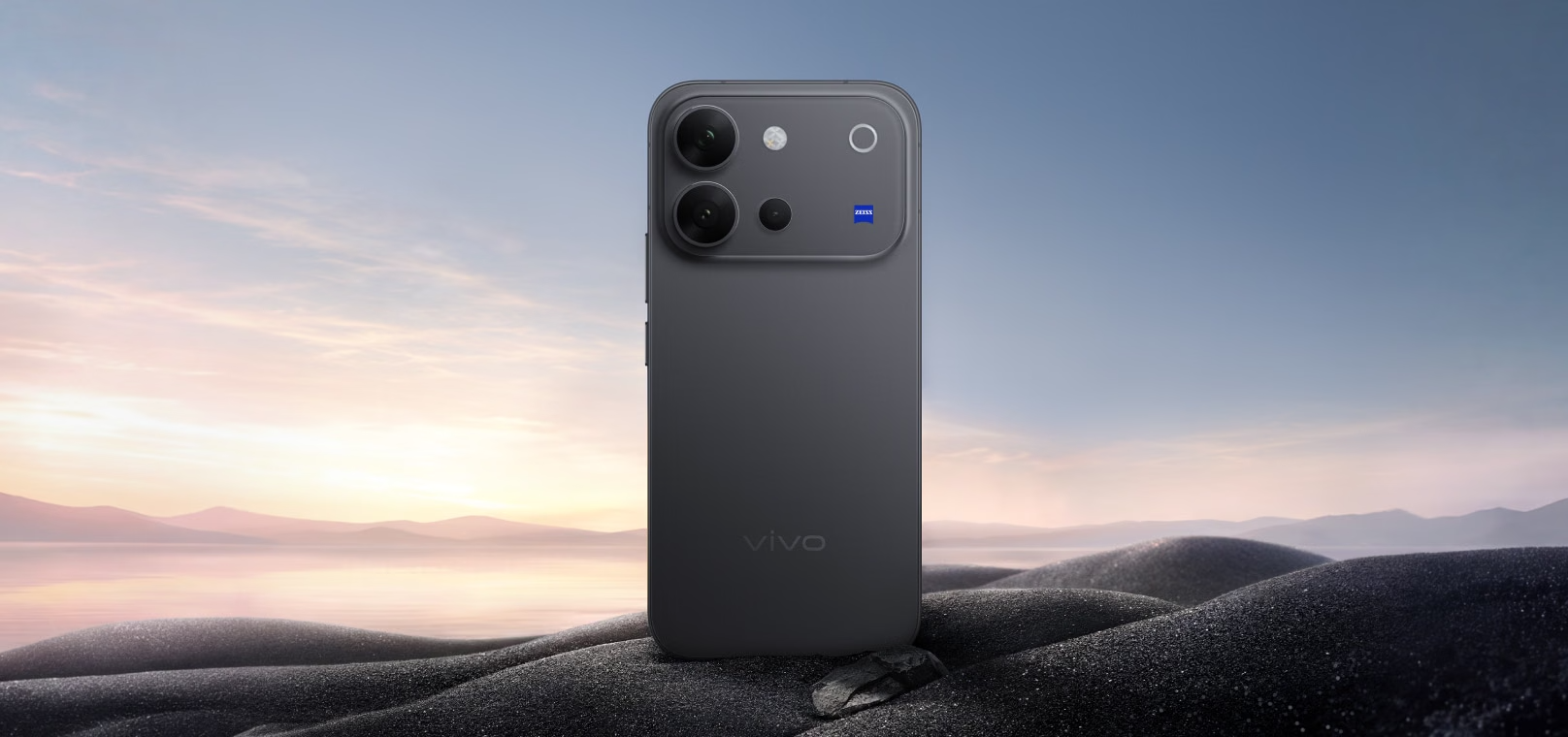 Vivo V80 in Stellar Black against a sunrise landscape